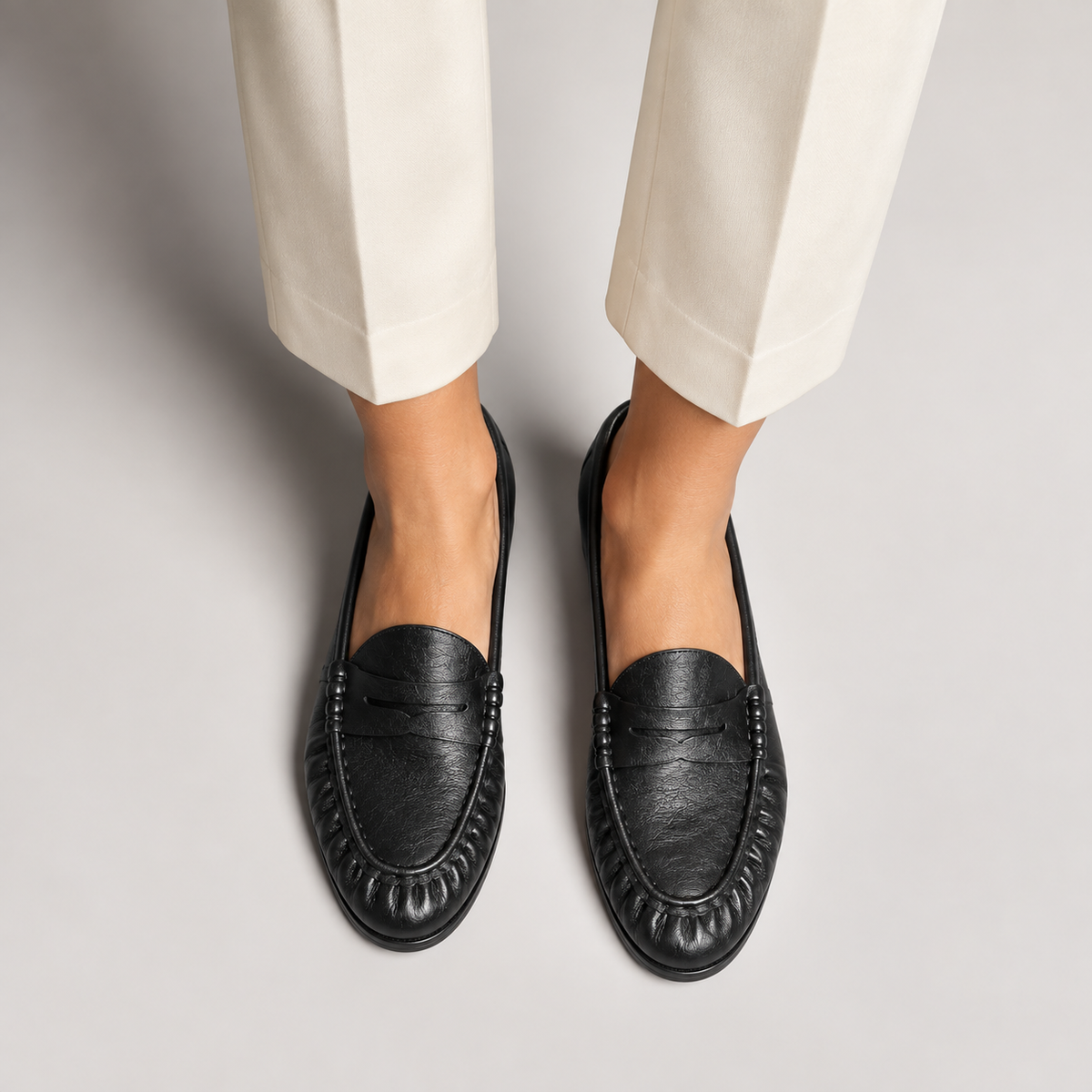 Mocassins noirs femme portés - Look élégant avec pantalon clair, cuir souple grainé, bout arrondi froncé et style premium quotidien.