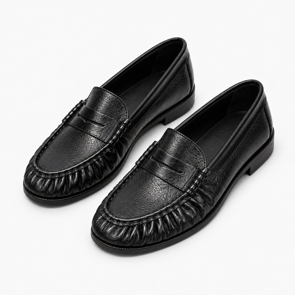 Paire de mocassins noirs femme en perspective - Cuir souple grainé, avant froncé, détails latéraux et rendu premium sur fond clair.