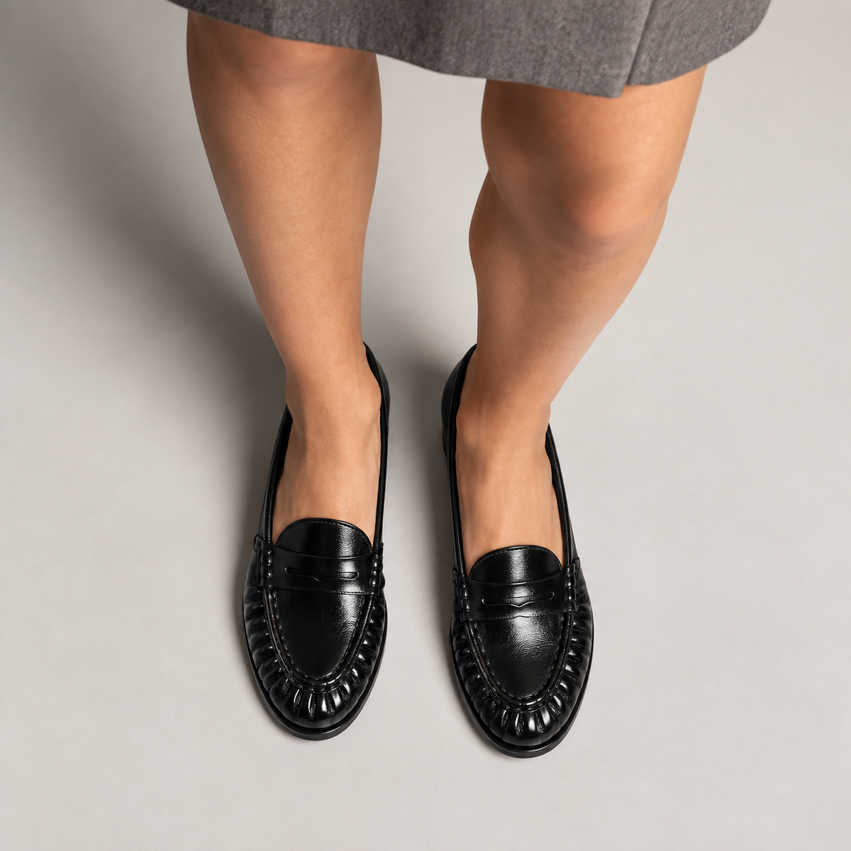 Mocassins noirs femme portes avec jupe grise, cuir brillant et style premium.